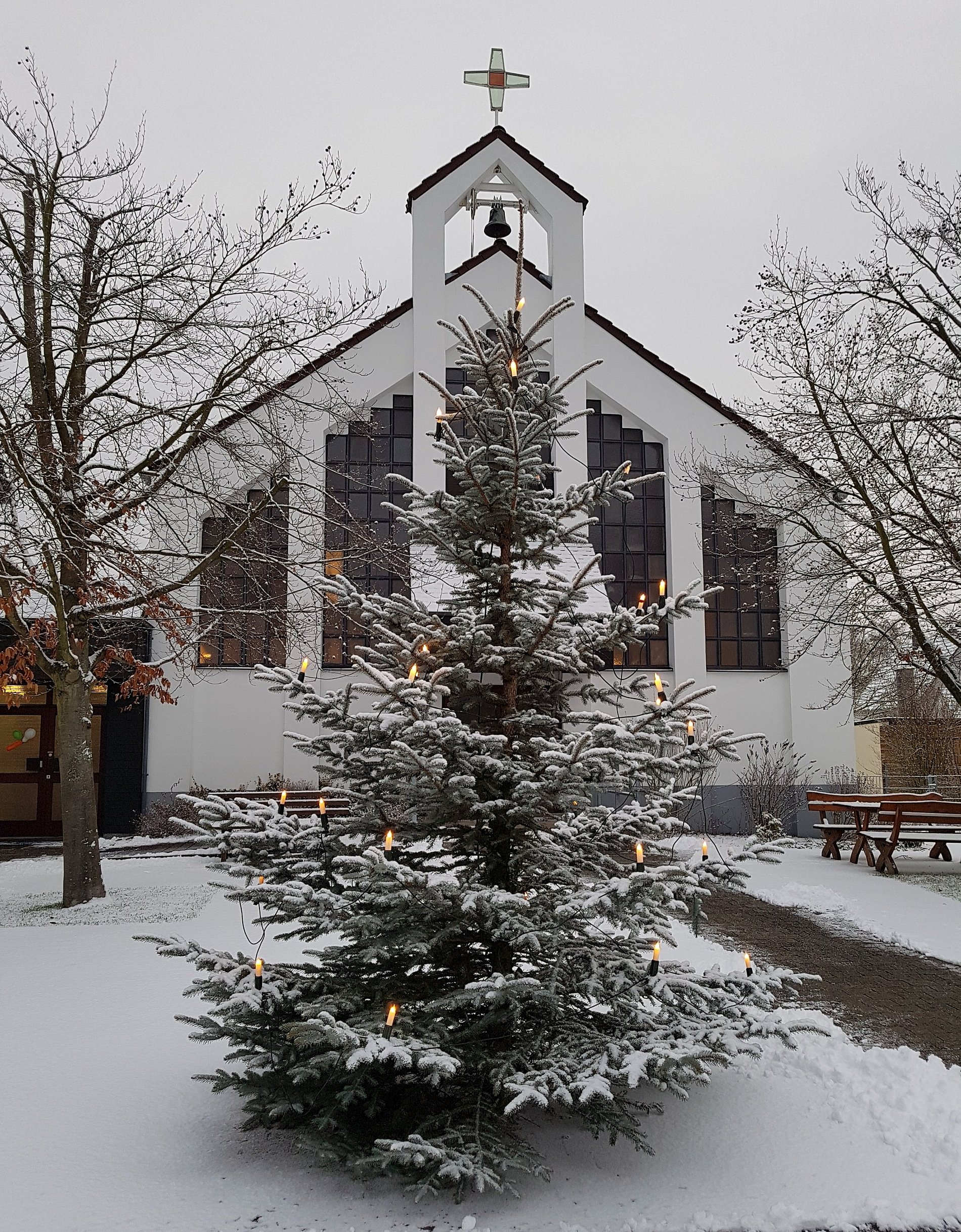 Außenansicht der Schwalbacher Kirche im Schnee mit Christbaum